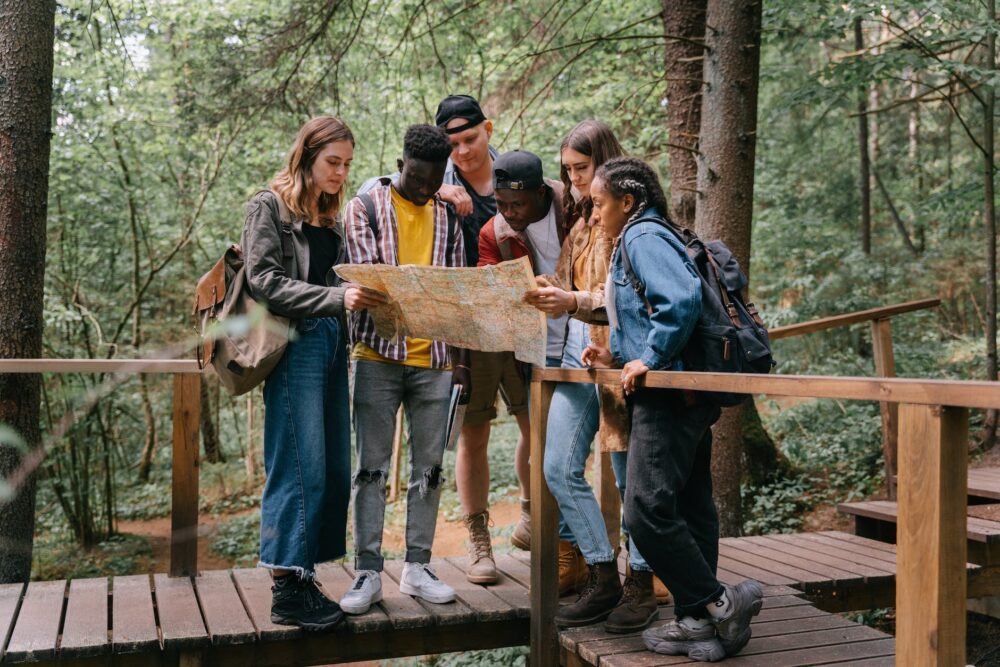 people standing on a wooden bridge while reading a map
