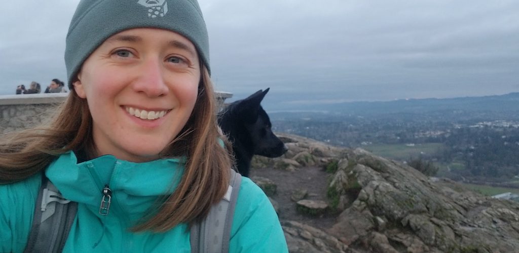 Person smiling with a dog behind them